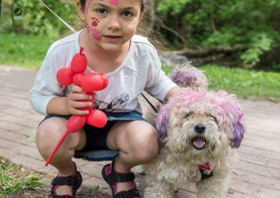 Little girl with painted face and her puppy dog with pink hair