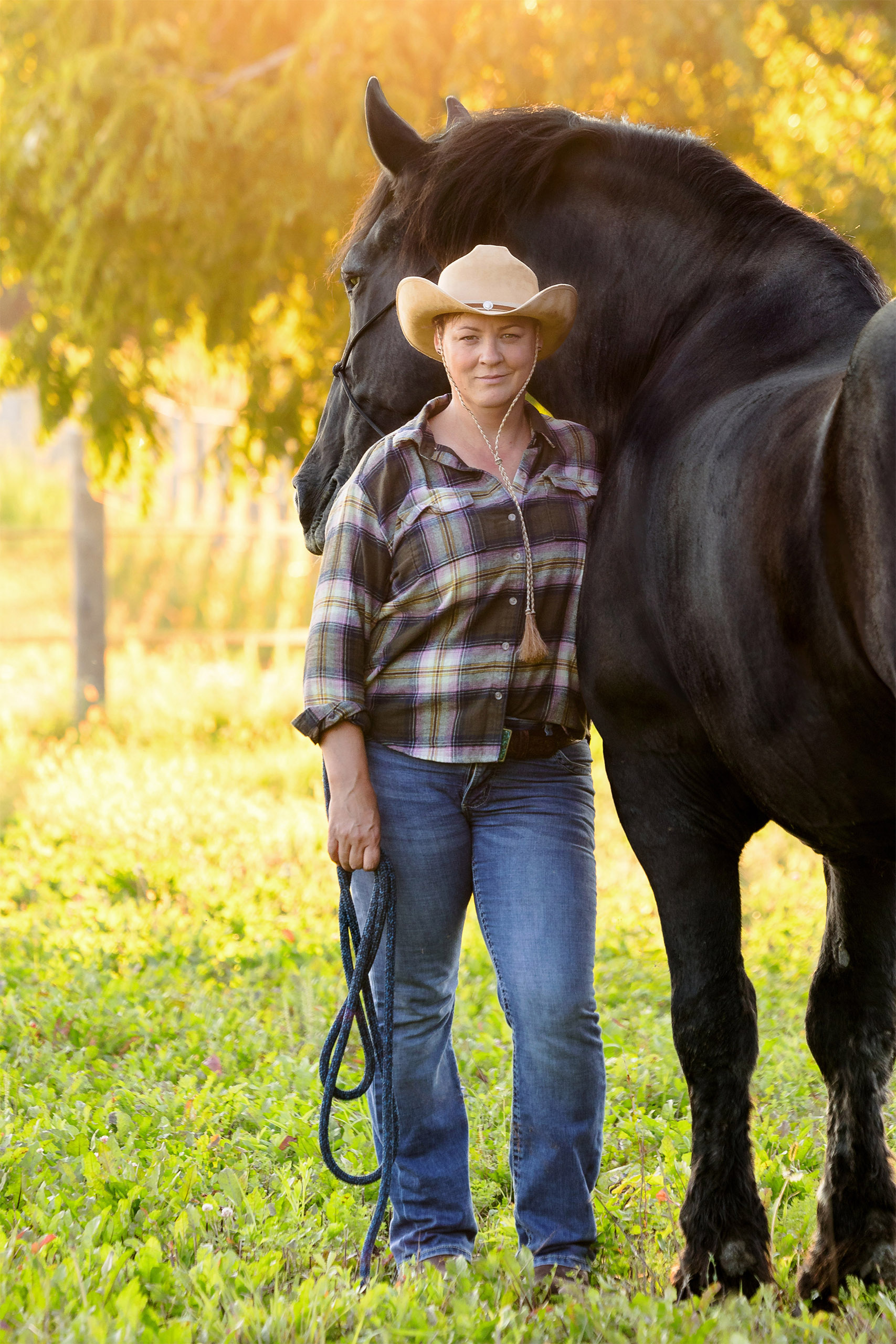 woman standing at horses shoulder facing camera with backlight